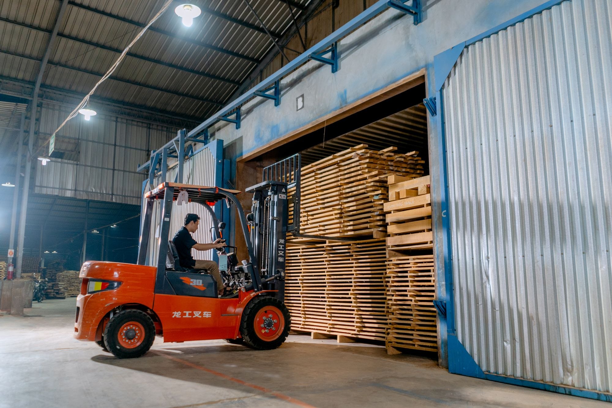 Forklift operator handling wooden pallets in a warehouse