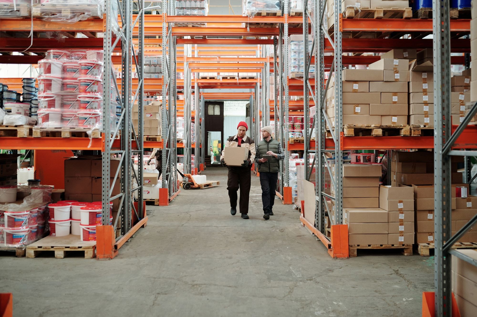 Two warehouse employees walking along a storage aisle